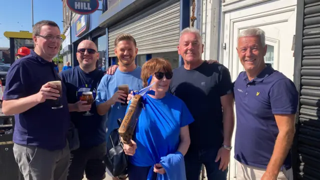 Smiling fans gather outside a pub near Goodison Park 