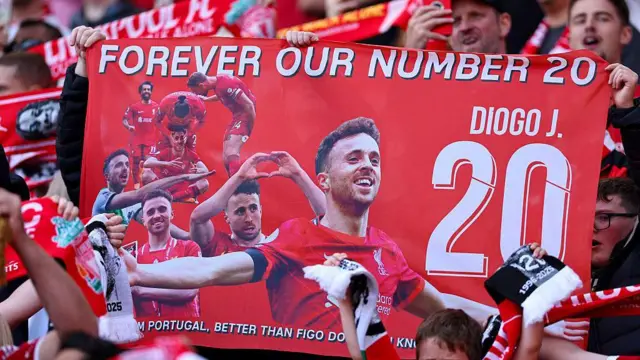 A fan holds up a poster of Diogo Jota