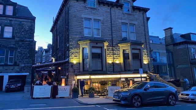 The exterior of William & Victoria wine bar, a four-storey brick building, in the evening.