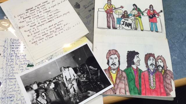 A black and white photo, cartoon drawings and written notes scattered on a table which belong to Paul Weller during his formative years.