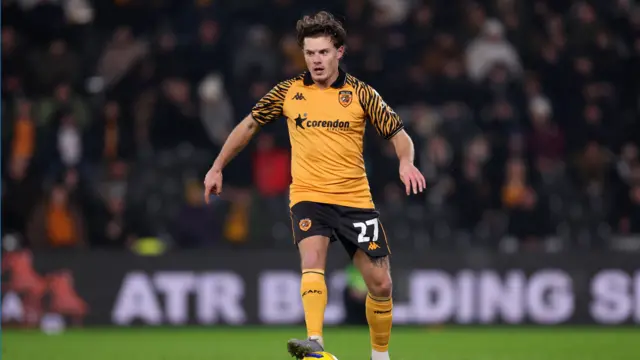 Midfielder Regan Slater playing for Hull City in the club's orange and black home shirt with the crowd behind him