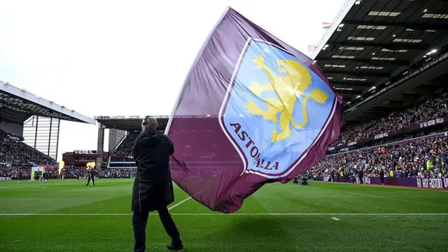 An Aston Villa flag is waved on the pitch before a match at Villa Park