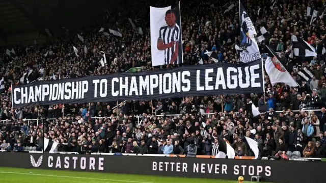 Newcastle fans holding banner saying "Championship to Champions League" banner