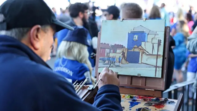 An artist paints outside Goodison before the match 