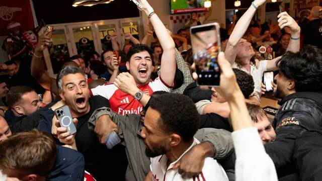Arsenal fans celebrate their team winning the Premier League, from inside the Tollington Arms pub 