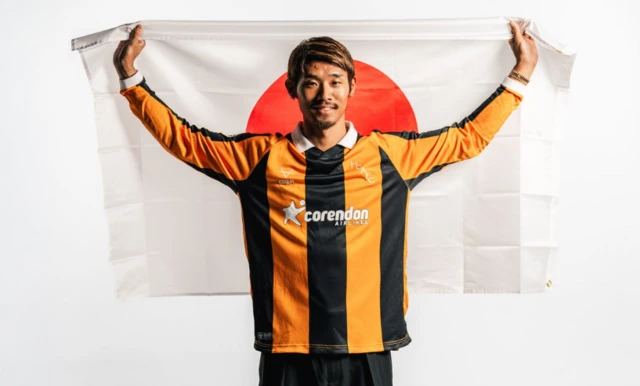 Hidemasa Morita poses wearing a Hull shirt and holding a Japan flag