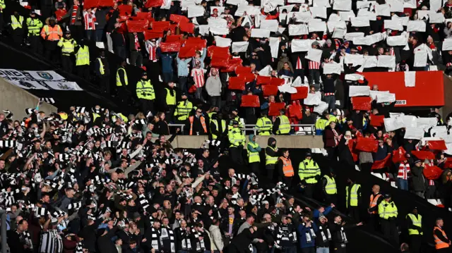 Image of Newcastle and Sunderland fans in stadium with line of stewards separating them 