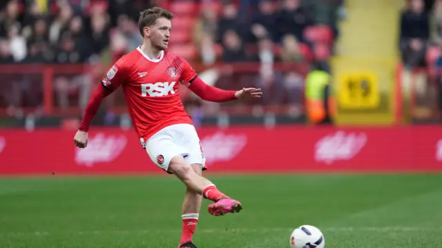 Luke Berry playing football in a Charlton Athletic home kit with the crowd in the background
