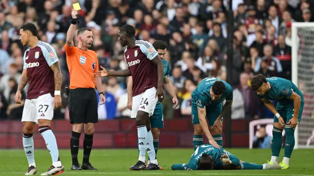 Match Referee, Chris Kavanagh shows a yellow card to Amadou Onana of Aston Villa during the Premier League match between Aston Villa FC and AFC Bournemouth at Villa Park