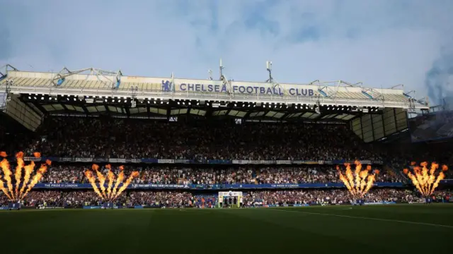 Stamford Bridge stadium in the sun with fireworks going off as the teams walk out on to the pitch