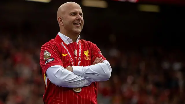 Arne Slot looks on smiling with Premier League winners medal