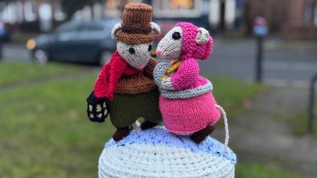 Two colourful knitted characters from the Charles Dickens' novella, 'A Christmas Carol'. The characters are mice and sit as a bollard topper.