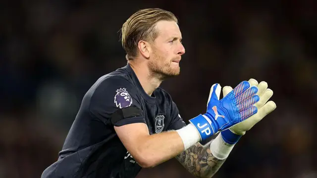 Jordan Pickford, wearing a dark-coloured Everton goalkeeper top and clapping his gloves together