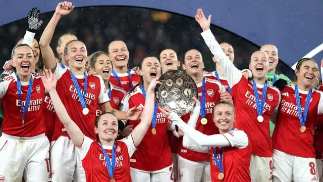 An image of Arsenal players celebrating with the Champions Cup trophy