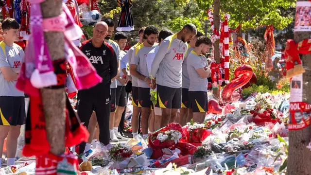 Liverpool players stand with their heads bowed at Anfield