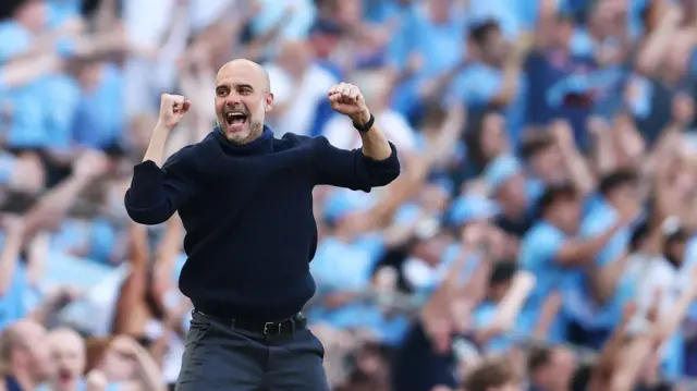 Pep Guardiola celebrates a Manchester City goal on the touchline