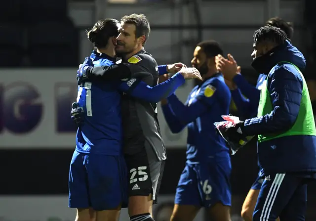 Alex Smithies, in a grey goalkeeper's kit, embraces as Cardiff City teammamte in celebration after a game