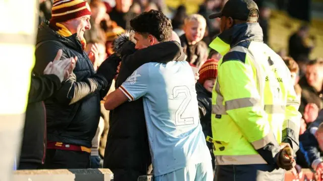 Elijah Just hugs a fan at full-time 
