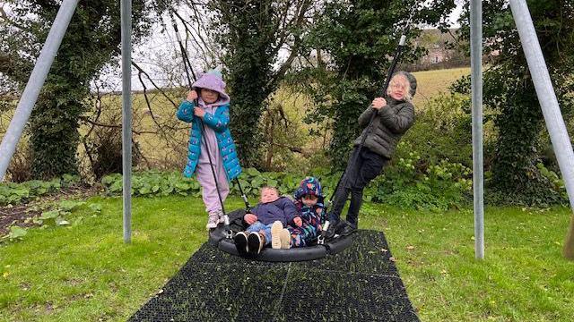 Four kids having fun on a birds nest swing