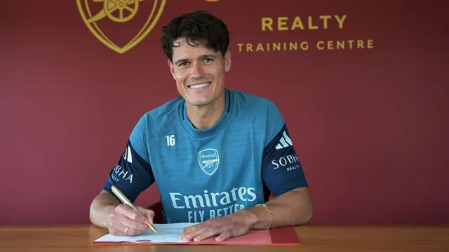 Christian Norgaard smiling and signing his Arsenal contract
