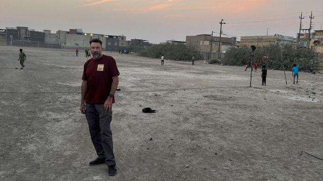 Ben Soppitt pictured with children playing football at the war grave site