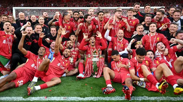 Liverpool's squad lies in from of the Kop with the Premier League trophy