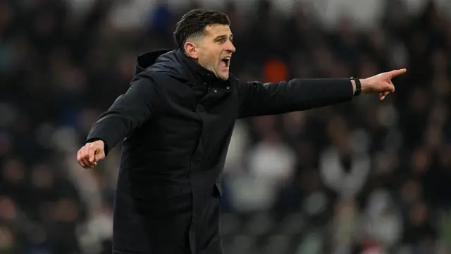 Portsmouth boss John Mousinho points from the sidelines in his black coat during the Derby County v Portsmouth game