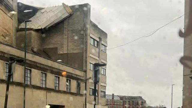 Roof hanging off top of building on grey day.