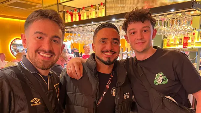 Two Manchester United fans pose for a picture with former Manchester United player Rafael
