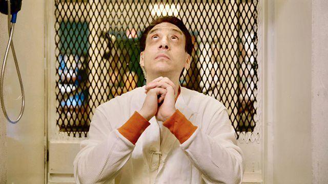 Ivan Cantu is wearing white prison overalls with orange cuffs with his hands clasped