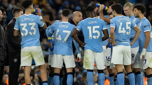 Manchester City players group around Pep Guardiola