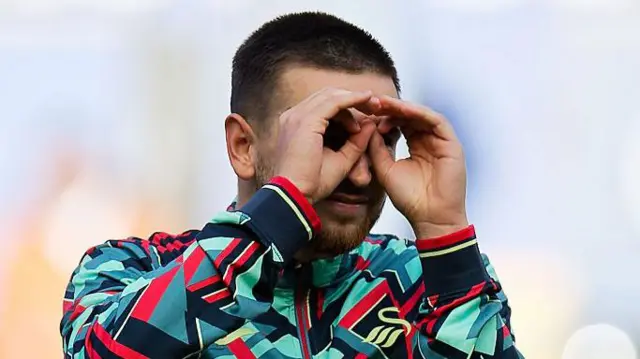 Zan Vipotnik in a Swansea City training top cupping his eyes with his hands to mimic spectacles