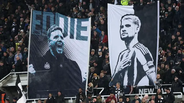 Fans holding up banners showing Eddie Howe and Bruno Guimaraes