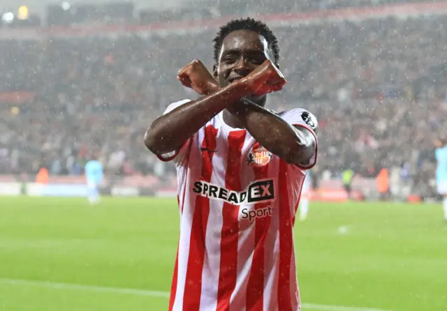 Abdoullah Ba makes an X with his arms in the rain while wearing Sunderland's home kit.