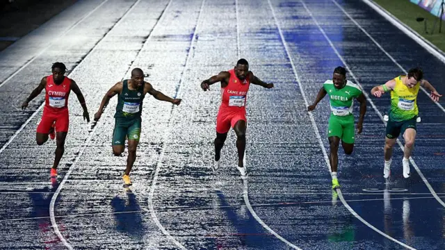 Jeremiah Azu of Team Wales, Gift Leotlela of Team South Africa, Emmanuel Eseme of Team Cameroon and Kayinsola Ajayi of Team Nigeria cross the finish line in the Men's 100 Metres Final 