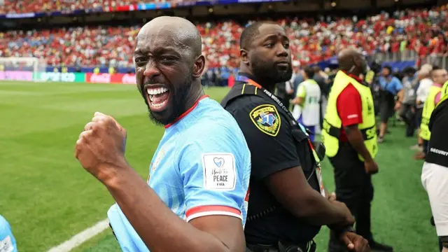 Yoane Wissa punches the air and looks at the camera as he celebrates