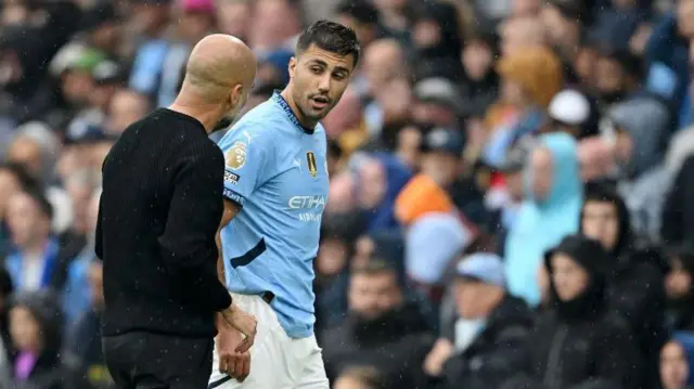 Rodri of Manchester City talks to Pep Guardiola after leaving the pitch due to an injury