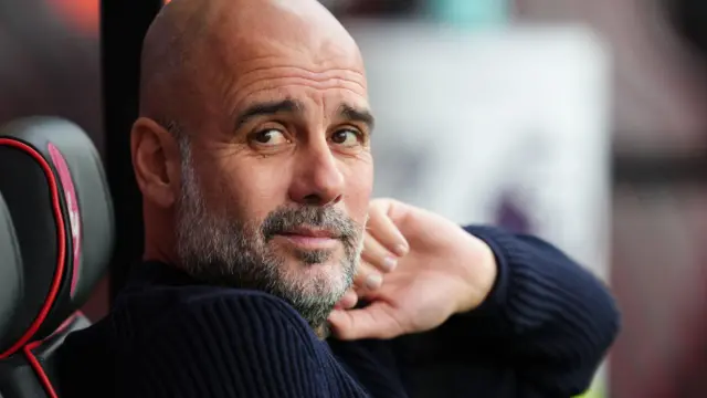 Pep Guardiola sits in the dugout