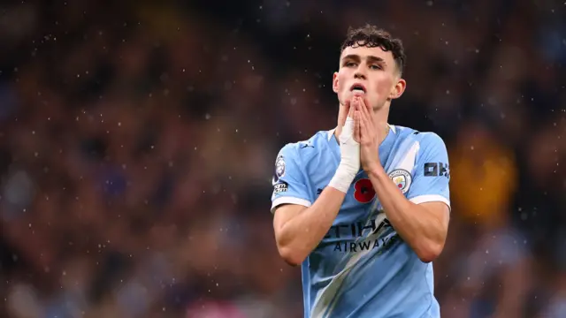 Phil Foden has hands together near his face while wearing white wrist and hand taping on his right hand