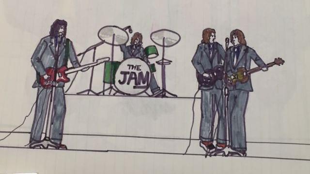 A cartoon drawing by singer-songwriter Paul Weller which features a music band with four members, wearing dark grey suits. There is also a drum kit which has the band name The Jam labelled on it.
