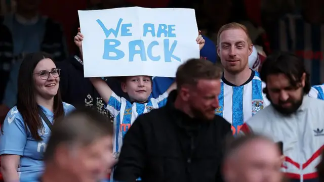 A young Coventry City fan at the Emirates holds a 'We are back' sign
