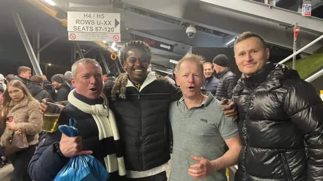 A group of four men pose for a picture on the concourse