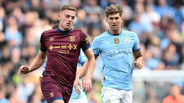 Liam Delap of Ipswich Town makes a pass while under pressure from John Stones of Manchester City