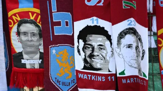 A detailed view of scarves featuring Unai Emery, Ollie Watkins and Emiliano Martinez being sold outside Villa Parl