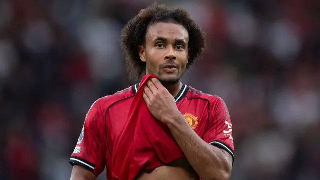 Joshua Zirkzee holds part of shirt and looks on during match for Manchester United