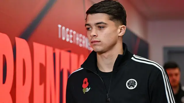 Lewis Miley, wearing a black Newcastle training top, looks serious in the tunnel before the game at Brentford