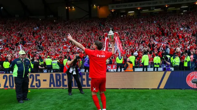 Graeme Shinnie shows off the trophy to the fans