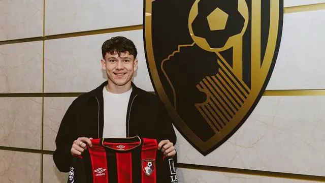 Alex Toth holds up Bournemouth shirt in front of badge