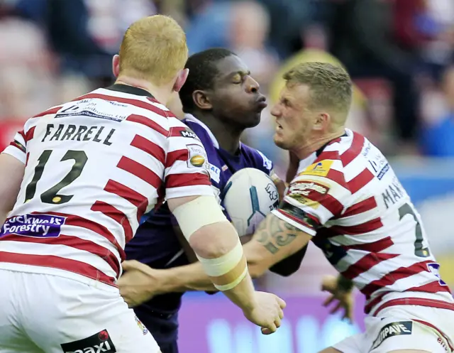 Huddersfield's Jermaine McGillvary is stopped by Liam Farrell and Dom Manfredi