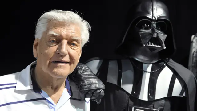 Dave Prowse poses next to a statue of Darth Vader